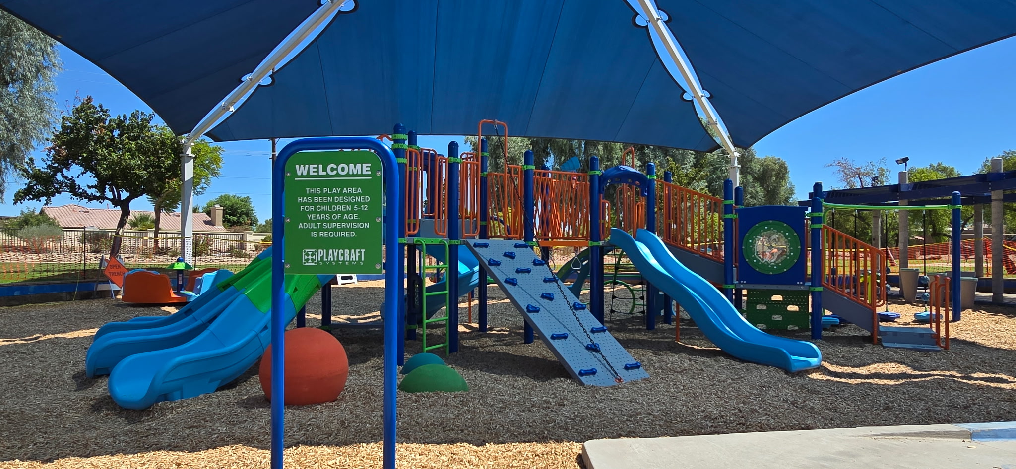 Full view of the new Adams Park playground in La Quinta featuring shaded play areas, swings, and colorful equipment installed by Pacific Play Systems.
