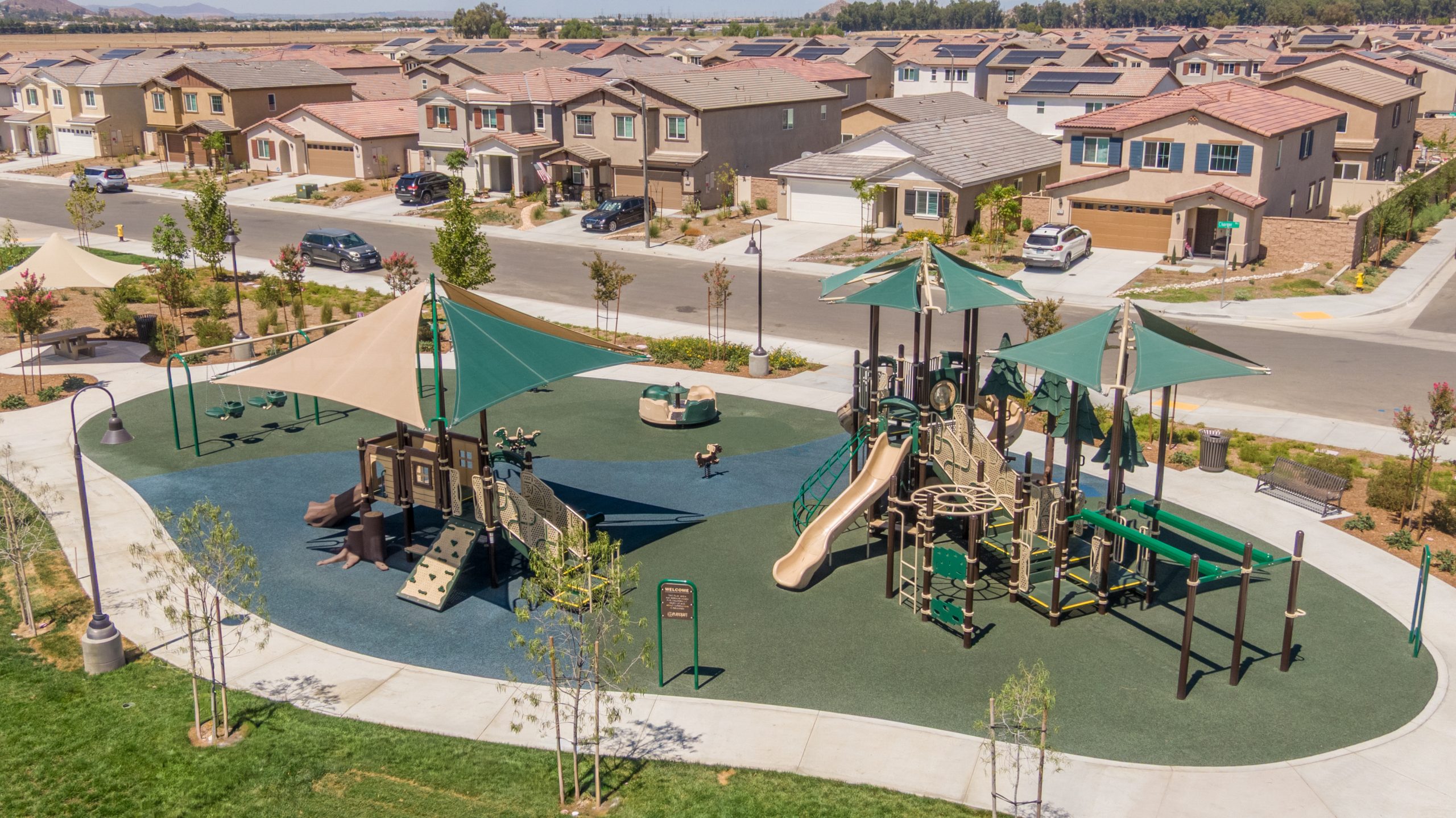 La Pradera South Park playground in Winchester, CA featuring brown and forest green play structures, slides, swings, spinners, and safe PIP surfacing